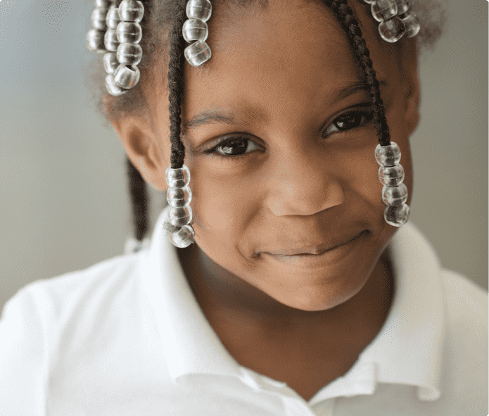 Portrait of a smiling child with braided hair and clear beads, wearing a white shirt
