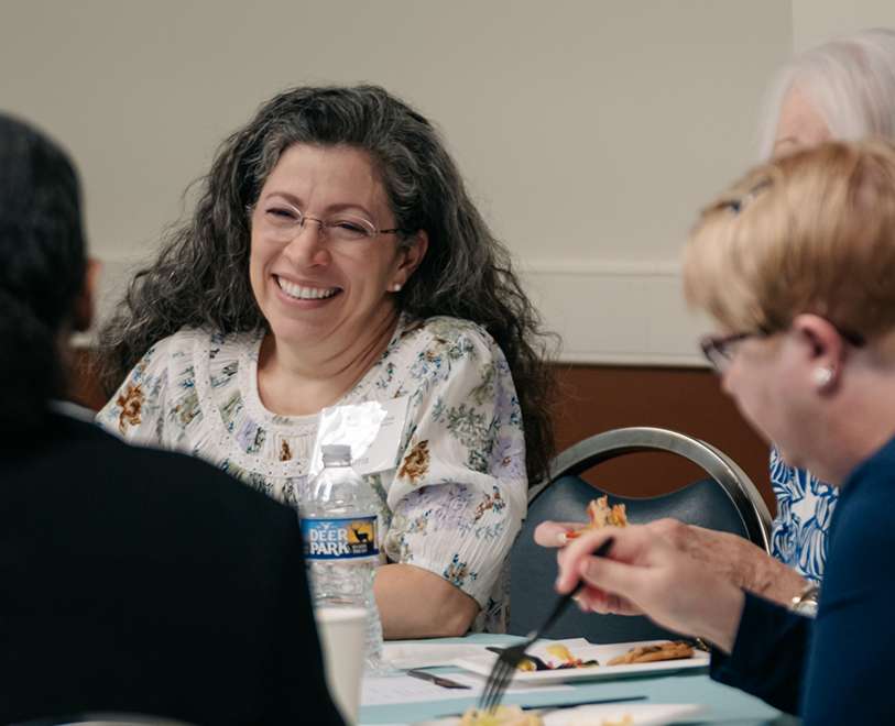 Woman smiling at a table during a group meal or meeting