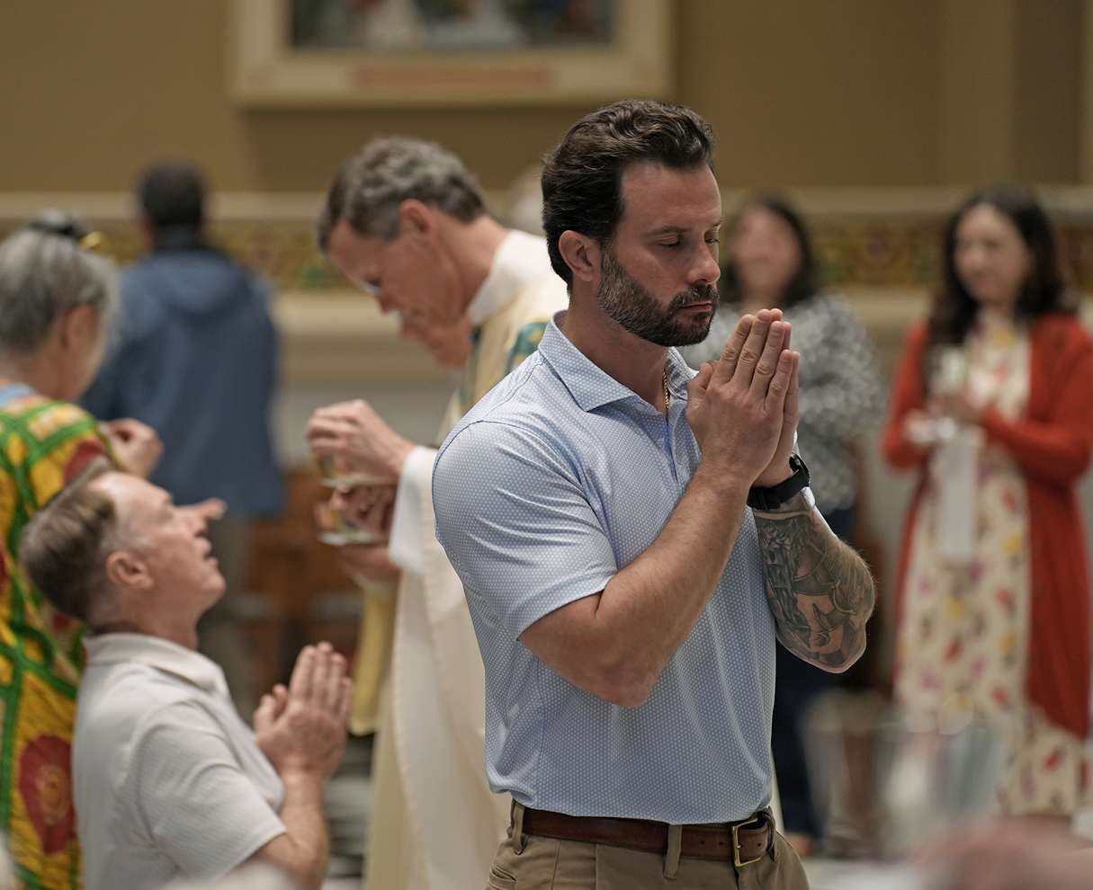 Man praying with hands clasped in a church service