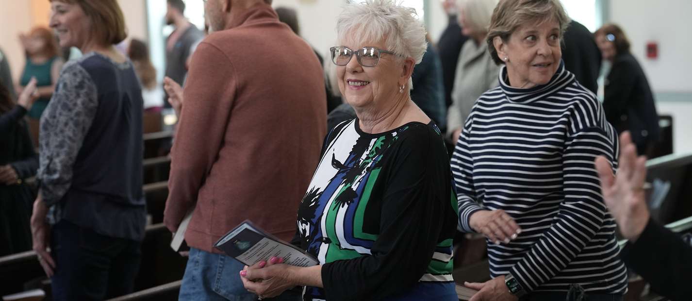 Older women standing and chatting in a church or community gathering